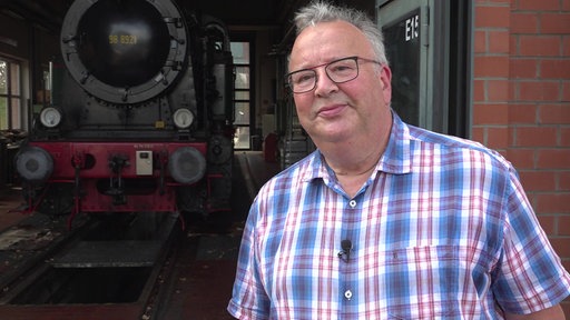 Franz Schmitz vom "Arbeitskreis Schluff" ist im Porträt zu sehen. Im Hintergrund steht die alte Museumsbahn.