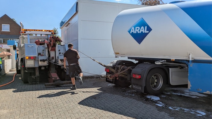 Ein Abschleppwagen versucht, einen Tanklaster aus einem engen Hof zu ziehen