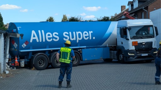 Ein Mann vom THW steht mit dem Rücken zur Kamera, im Hintergrund ein verkeilter Tanklaster
