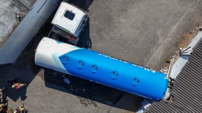 Der Anhänger des Tanklasters ist quer zwischen Garagen und einem Gebäude verkeilt