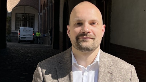 Vincent Bölting schaut direkt in die Kamera. Im Hintergrund 