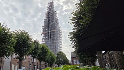 Marktplatz im Dorf Walbeck mit eingerüstetem Kirchturm von St. Nikolaus, Baugerüste um die Kirche.