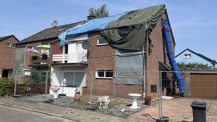 Um das betroffene Haus sind mehrere Planen gespannt und Zäune wurden vor dem Haus abgestellt