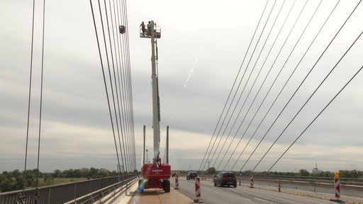Ein Kran hebt Arbeiter in große Höhe an der Rheinbrücke Rees für den Robotereinsatz