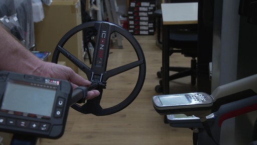 Ein Metalldetektor wird in der Hand gehalten
