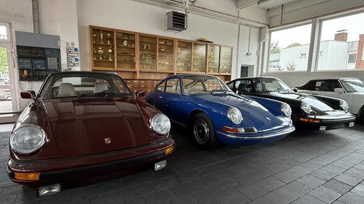 Porsche-Oldtimer stehen in einer Reihe nebeneinander in einer Halle