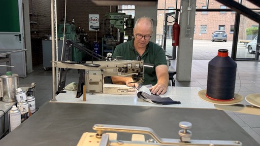 Guido Hollands arbeitet an einer Nähmaschine in einer Autowerkstatt