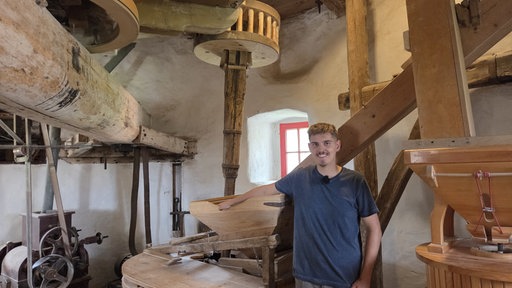 Ein junger Mann steht im Inneren einer Mühle.