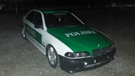 Ein Auto in dem grün-weiß älterer Polizeiautos mit der Aufschrift "Polisei".