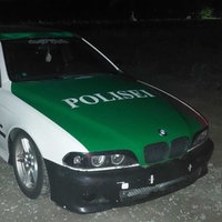 Ein Auto in dem grün-weiß älterer Polizeiautos mit der Aufschrift "Polisei".