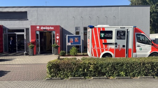 Ein Rettungswagen steht vor einem Caritas-Gebäude, das mit "Alfred-Delp-Haus" überschrieben ist