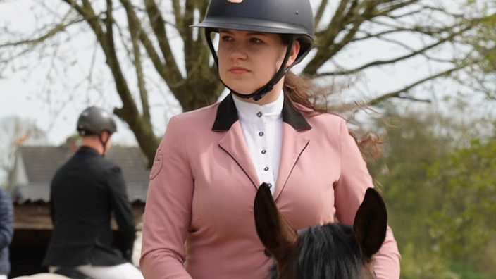 Anni Ketteler sitzt auf ihrem Pony Robby mit Kappe und rosa Jackett