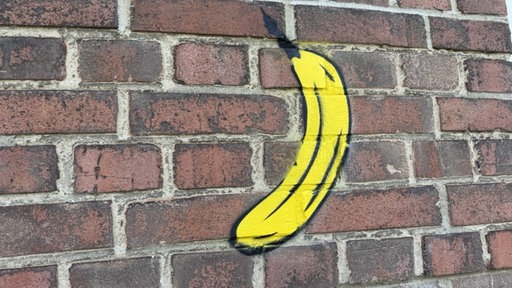 Auf einer Backsteinwand ist das Graffiti von einer Banane