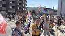 Viele Demonstrierende laufen über eine Straße und halten Regenbogenfahnen.