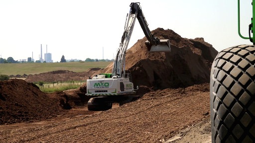 Bagger schüttet Deich auf