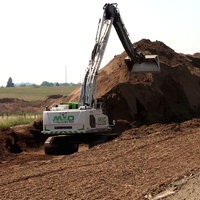 Bagger schüttet Deich auf