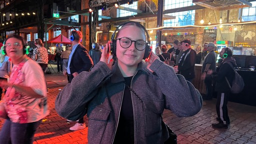 Lea Skrzipietz andere Partygäste im Hintergrund mit Kopfhörern über den Ohren