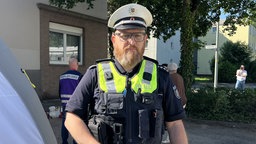 Ein Polizist in Dienstkleidung schaut ernst in die Kamera.