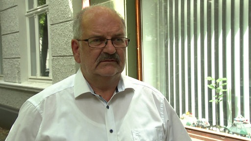 Ein Mann in weißem Hemd steht vor einem Schaufenster