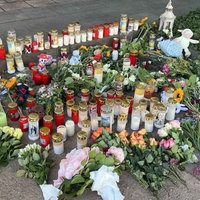 Auf einem Straßenstück liegen zahlreiche Blumen, Grabkerzen und Stofftiere 