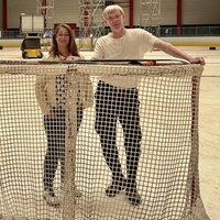 Frau und Mann stehen auf Eisbahn hinter einem Hockey-Tor