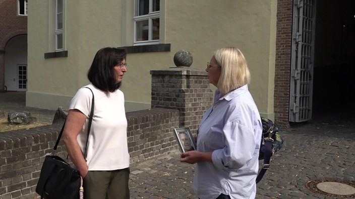 Die beiden Töchter des Verstorbenen stehen mit einem Foto ihres Faters vor dem Landgericht in Kleve.