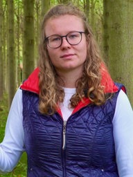 Hanna Bonsels steht neben einem Baumstamm