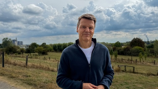 Ein Mann in einem dunklen Pullover steht am Rhein