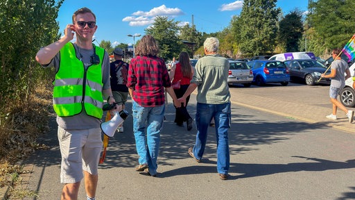 Ein Mann in einer gelben Warnweste steht mit Funkgerät in der Hand beim CSD in Moers