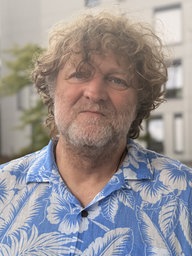 Mann mit Locken schaut in Kamera