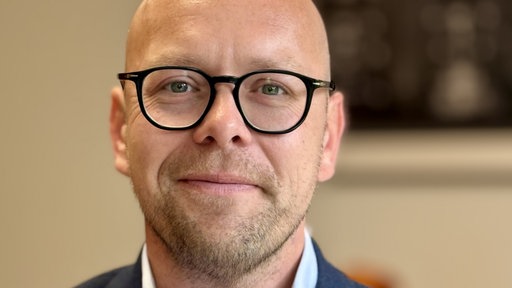 Ein Mann mit Brille lächelt in die Kamera