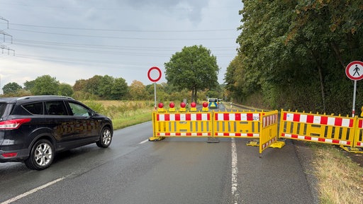 Ein Auto fährt an einer geöffneten Straßensperrung vorbei
