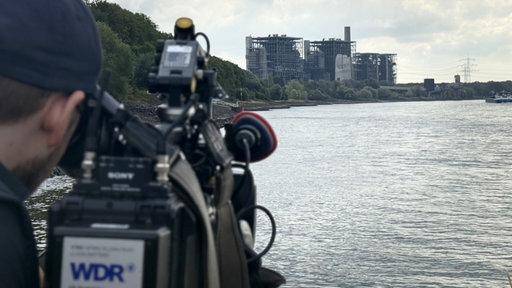 Im Vordergrund eine Kamera des WDR, im Hintergrund der Rhein und das Kraftwerk in Voerde
