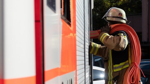 Einsatzkraft der Feuerwehr holt Einen Langen Schlauch aus dem Einsatzfahrzeug.