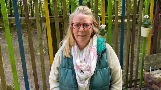 Eine Frau steht vor einem Zaun 