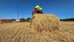 Zwei Feuerwehrmänner rollen einen Strohballen aus
