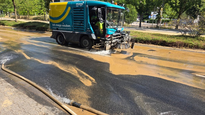Eine Kehrmaschine fährt auf einer überschwemmten Straße.