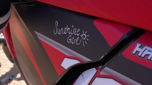 Nahaufnahme eines Motorcross- Bikes. Unter dem Sitz ist ein Schriftzug. "Sunshine Girl"