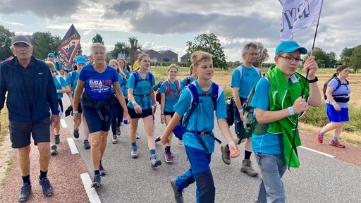 Kinder mit Fahnen wandern Straße entlang