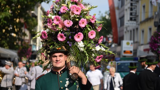 Ein Mann trägt ein Blumenhorn beim Neusser Schützenfest