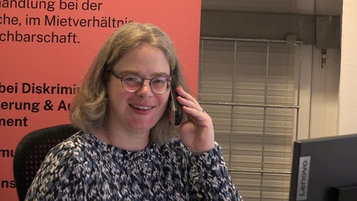 Frau mit Telefon am Ohr lächelt in die Kamera
