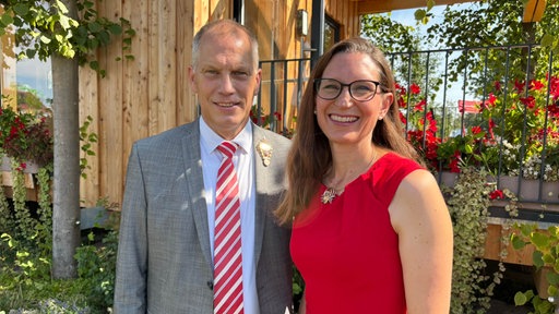 Das Neusser Königspaar 2026 Franz Josef und Claudia Odendahl steht vor dem Schützenhaus auf der LaGa mit viel Grün und roten Blumen
