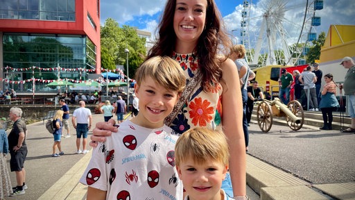 Eine Mutter steht mit ihren beiden Kindern beim Neusser Schützenfest