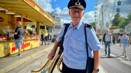 Ein Mann mit einer Tuba steht auf einer Straße