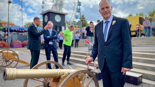 Ein Mann steht neben einer Kanone