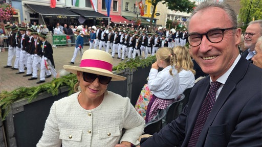 Ein Mann und eine Fraub lachen beim Neusser Bürgerschützenfest in die Kamera. 