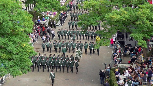 Schützen marschieren beim Schützenfest in Neuss. Sie haben grüne Uniformen an, das Bild ist aus einer erhöhten Position aufgenommen.
