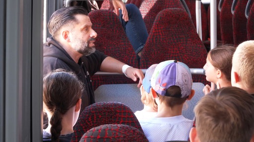Seminarleiter Micha Reinhardt gibt Kindern Tipps für den Selbstschutz in einem Bus