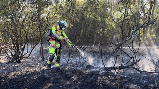 Ein Feuerwehrmann löscht den Brand