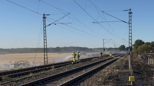 Einsatzkräfte löschen die Brände an der Bahnstrecke